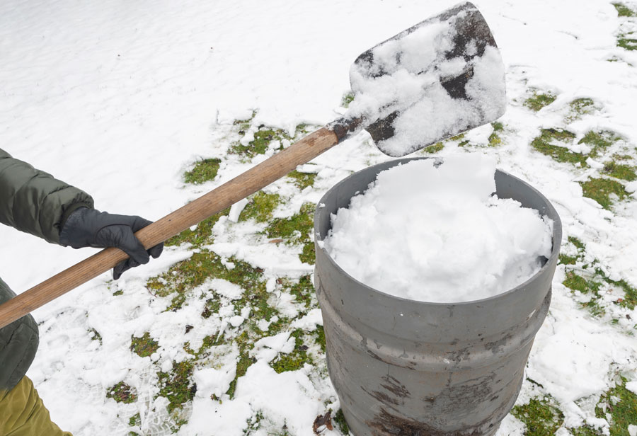 middle-aged-woman-is-collecting-snow-in-a-barrel-